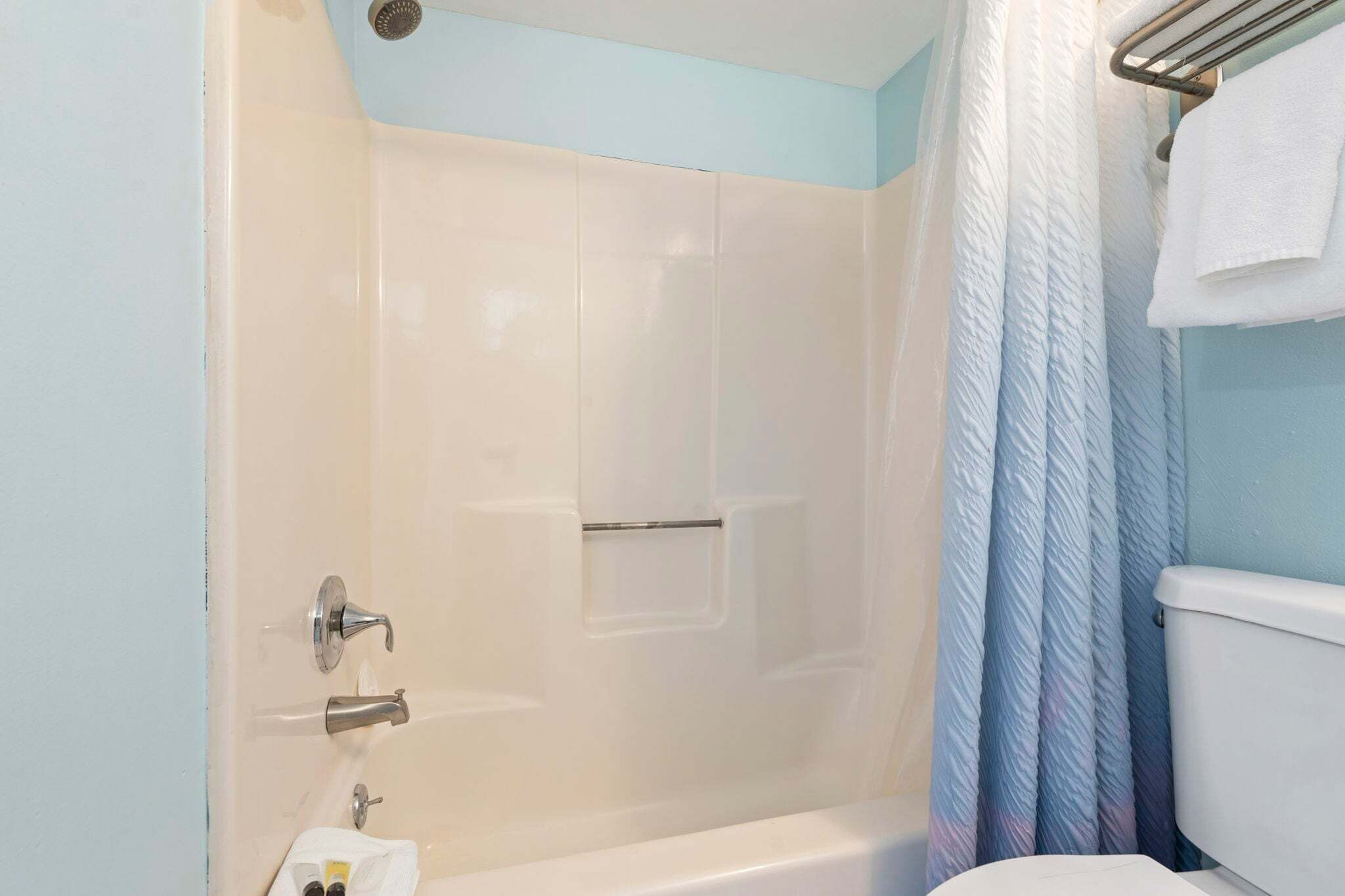 A bathroom with a shower, toilet, and towel rack.