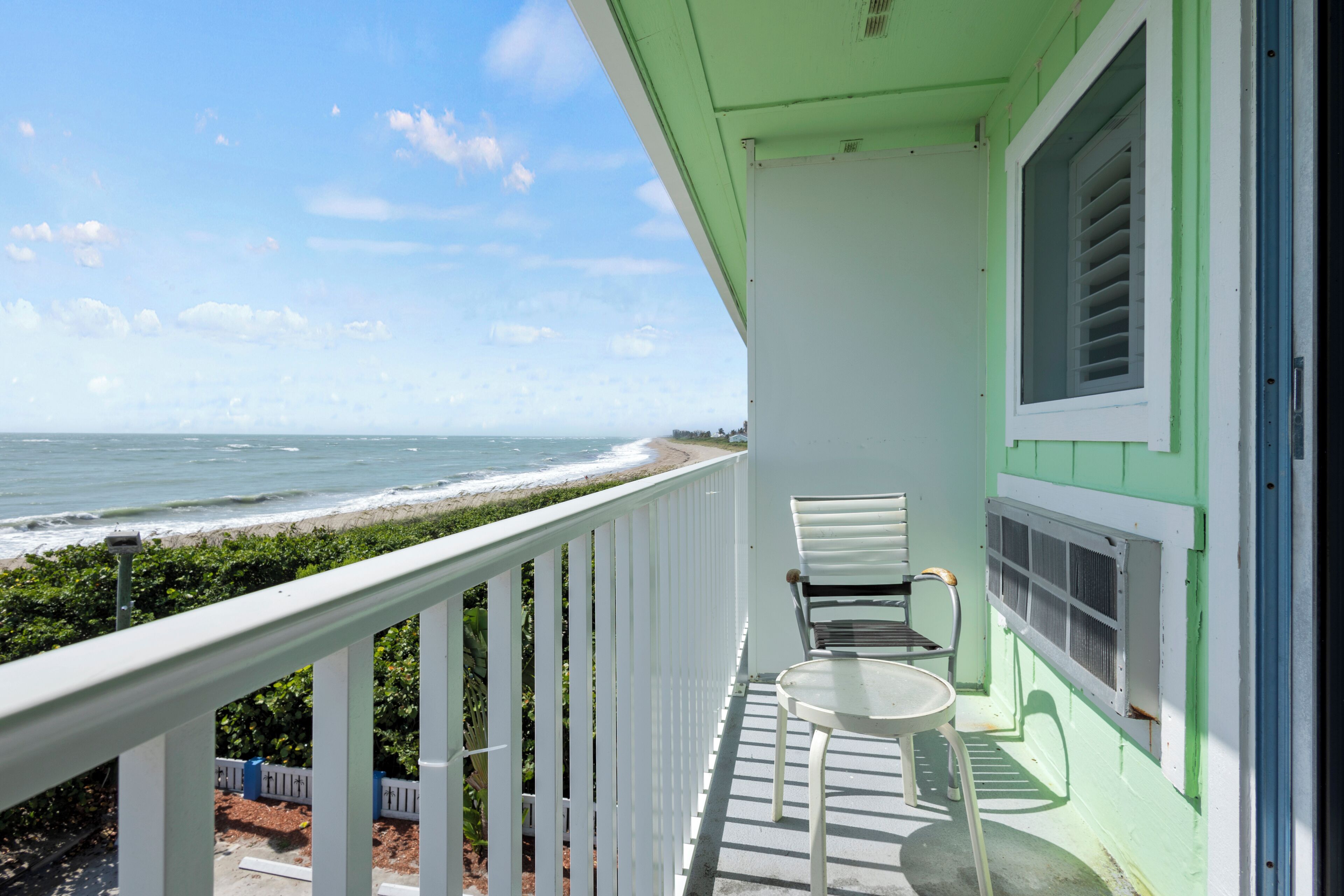 Ein Balkon mit Blick auf das Meer, einem weißen Geländer und zwei Stühlen.
