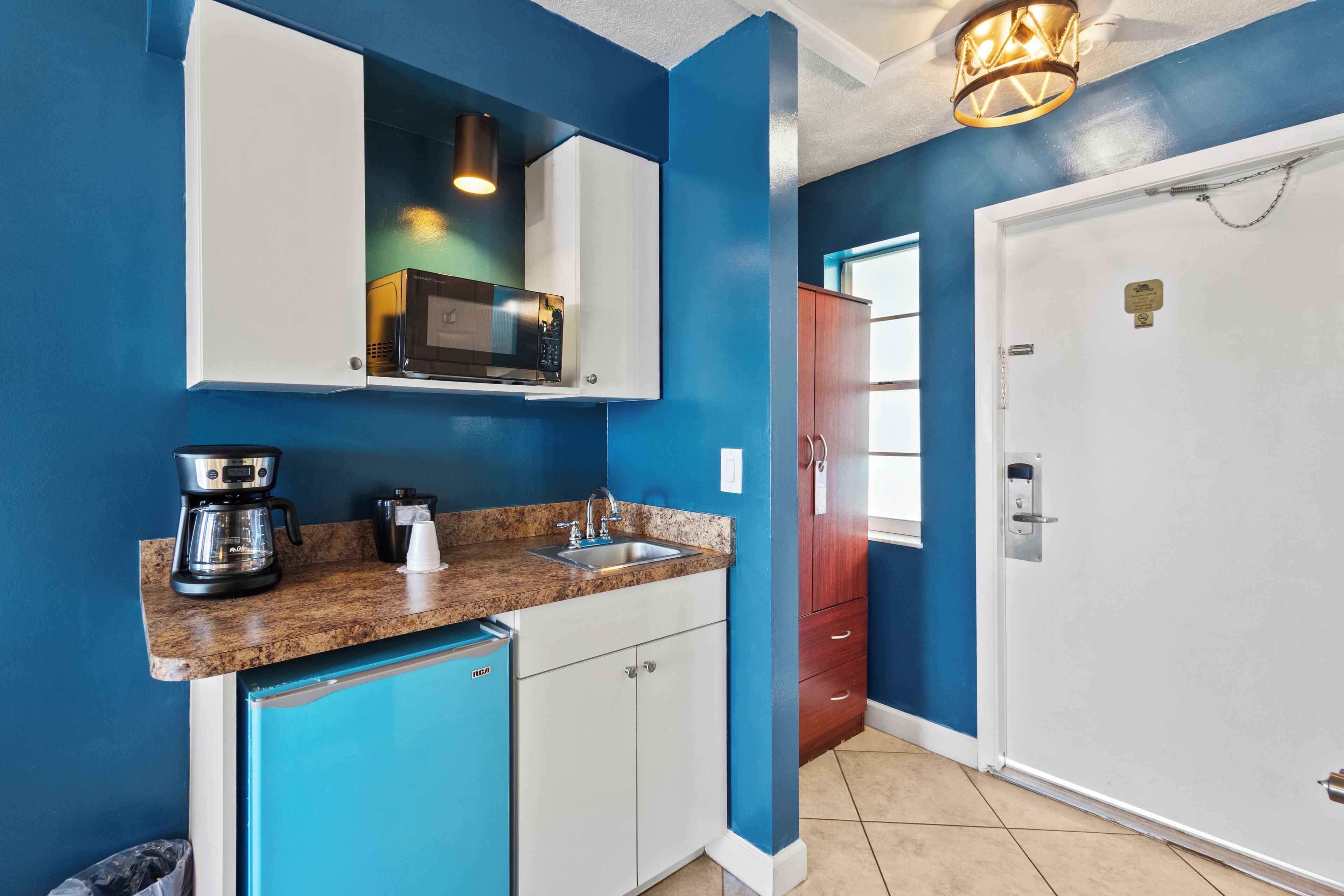 A compact kitchen with a microwave, coffee maker, and a sink.