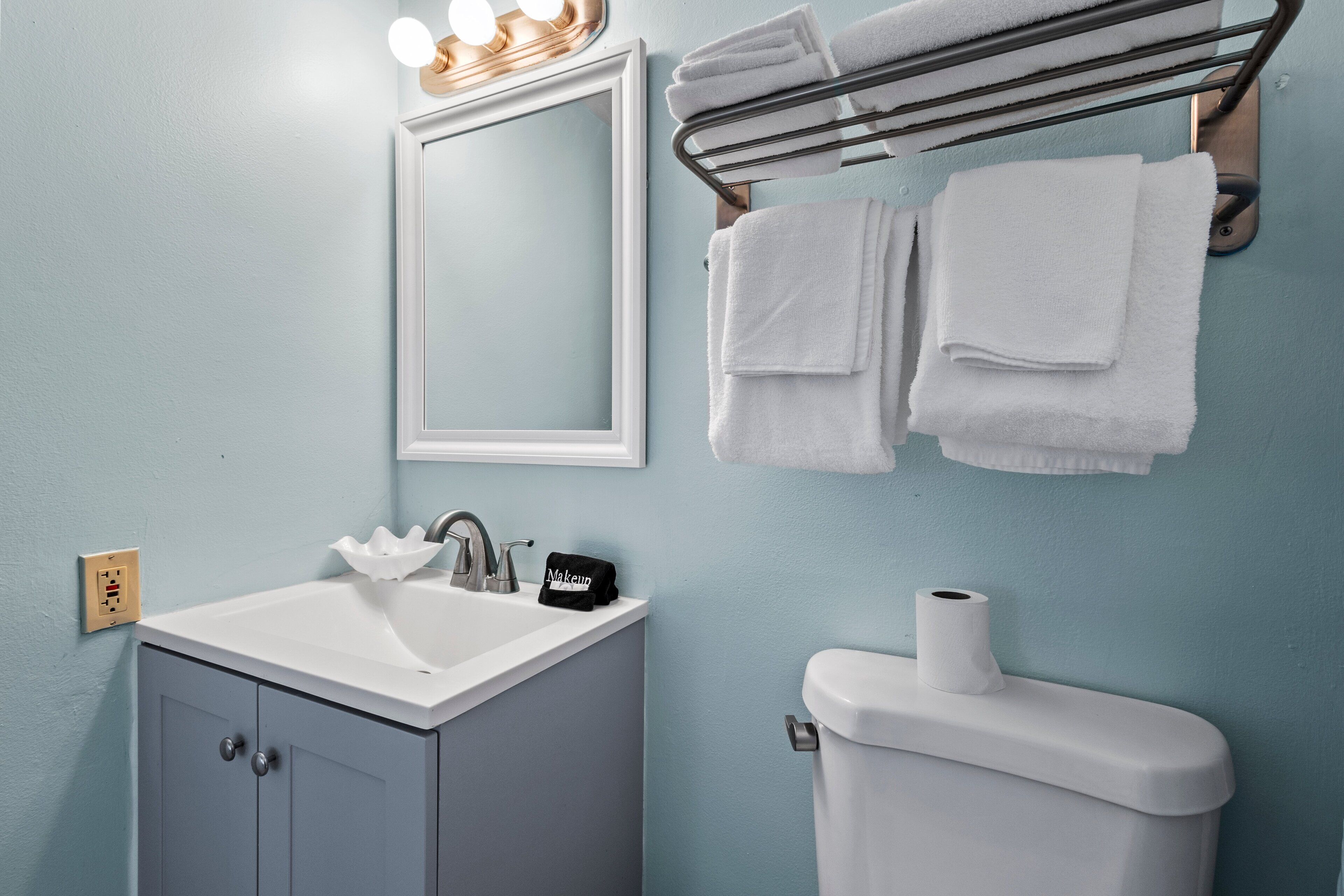 A bathroom with a sink, mirror, towel rack, and toilet.