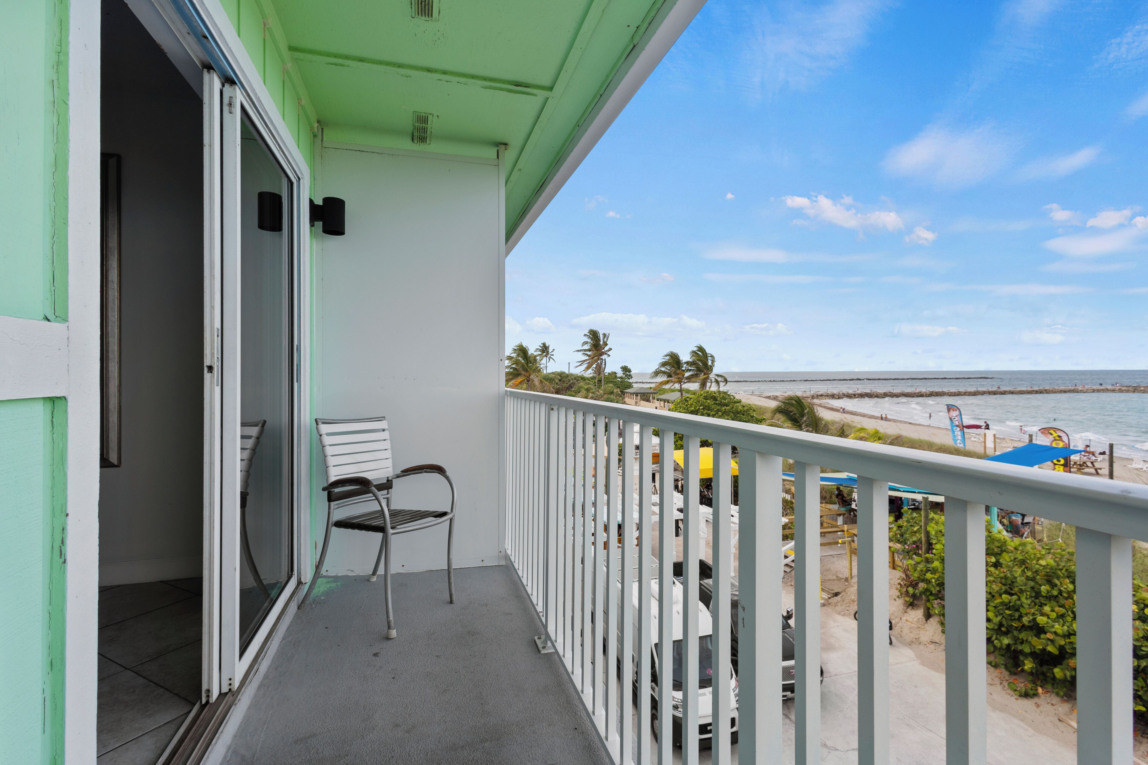 Een balkon met uitzicht op het strand, een stoel en een tafel.