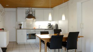 A modern kitchen with white cabinets, a wooden ceiling, and pendant lighting. - Apartment Wychel by Interhome (Grindelwald)