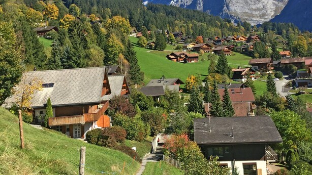 A mountain village with traditional wooden houses, a clear path leading to a chalet, and a snow-capped mountain in the background. - Apartment Wychel by Interhome (Grindelwald)