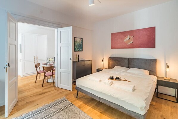 Un dormitorio moderno con una cama grande, mesitas de noche, cabecera y un cuadro en la pared.