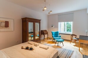 Un dormitorio con una cama grande, un armario, un escritorio, una silla y una ventana con vistas a la vegetación.