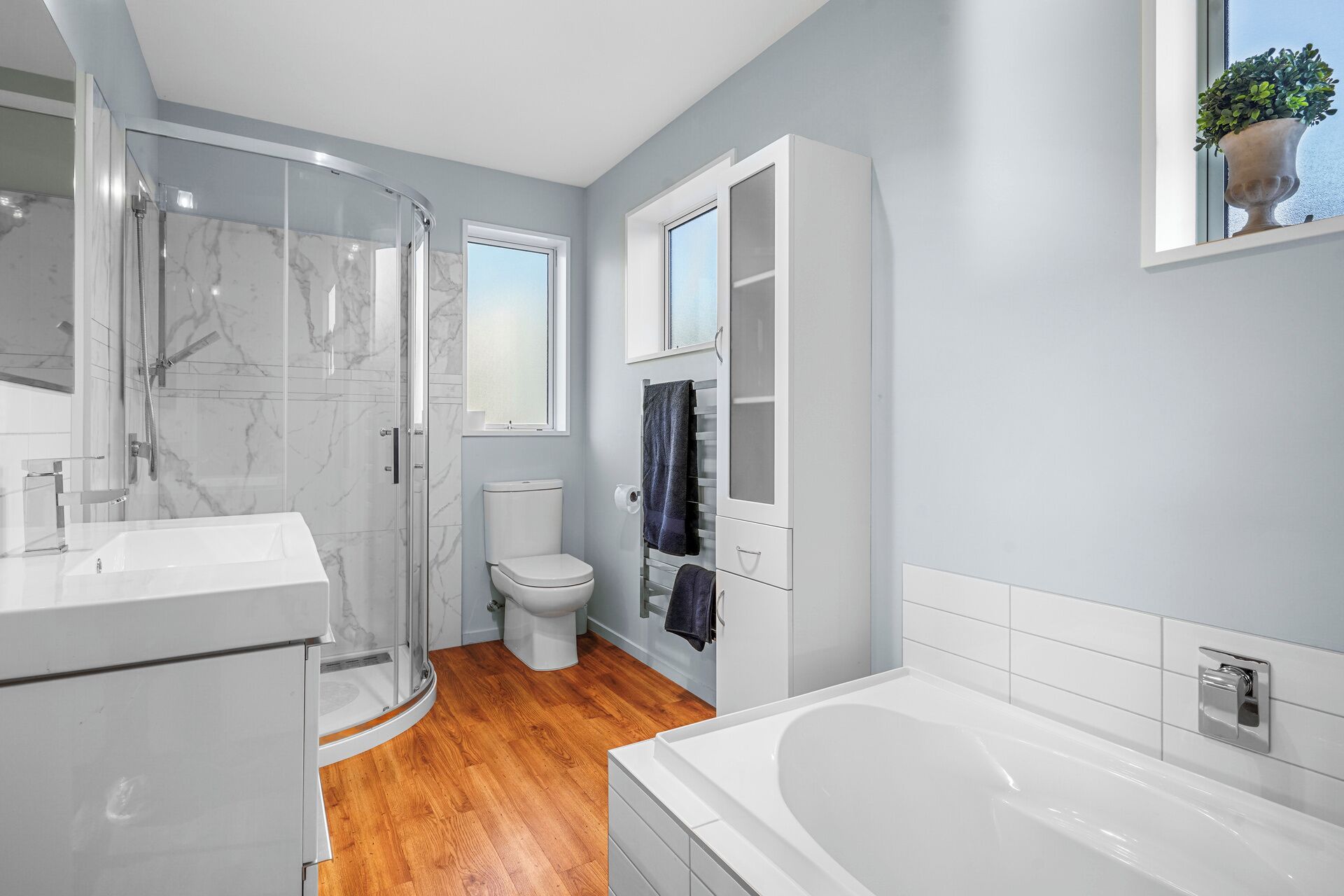 A modern bathroom with a glass shower enclosure, a toilet, and a bathtub.
