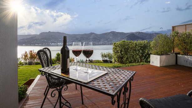 Eine Terrasse mit Tisch, zwei Weingläsern und einer Weinflasche.