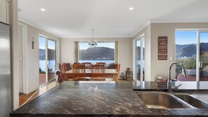 Eine moderne Küche mit Marmorarbeitsplatte, ein Essbereich mit Tisch und Stühlen sowie Meer- und Bergblick.