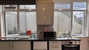 Keittiössä on pesuallas, mikroaaltouuni, vedenkeitin ja liesi. Siellä on myös kaappeja ja ikkuna, josta on näkymä aidalle.