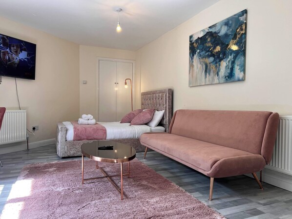 A modern bedroom with a bed, a sofa, a coffee table, and a painting on the wall.