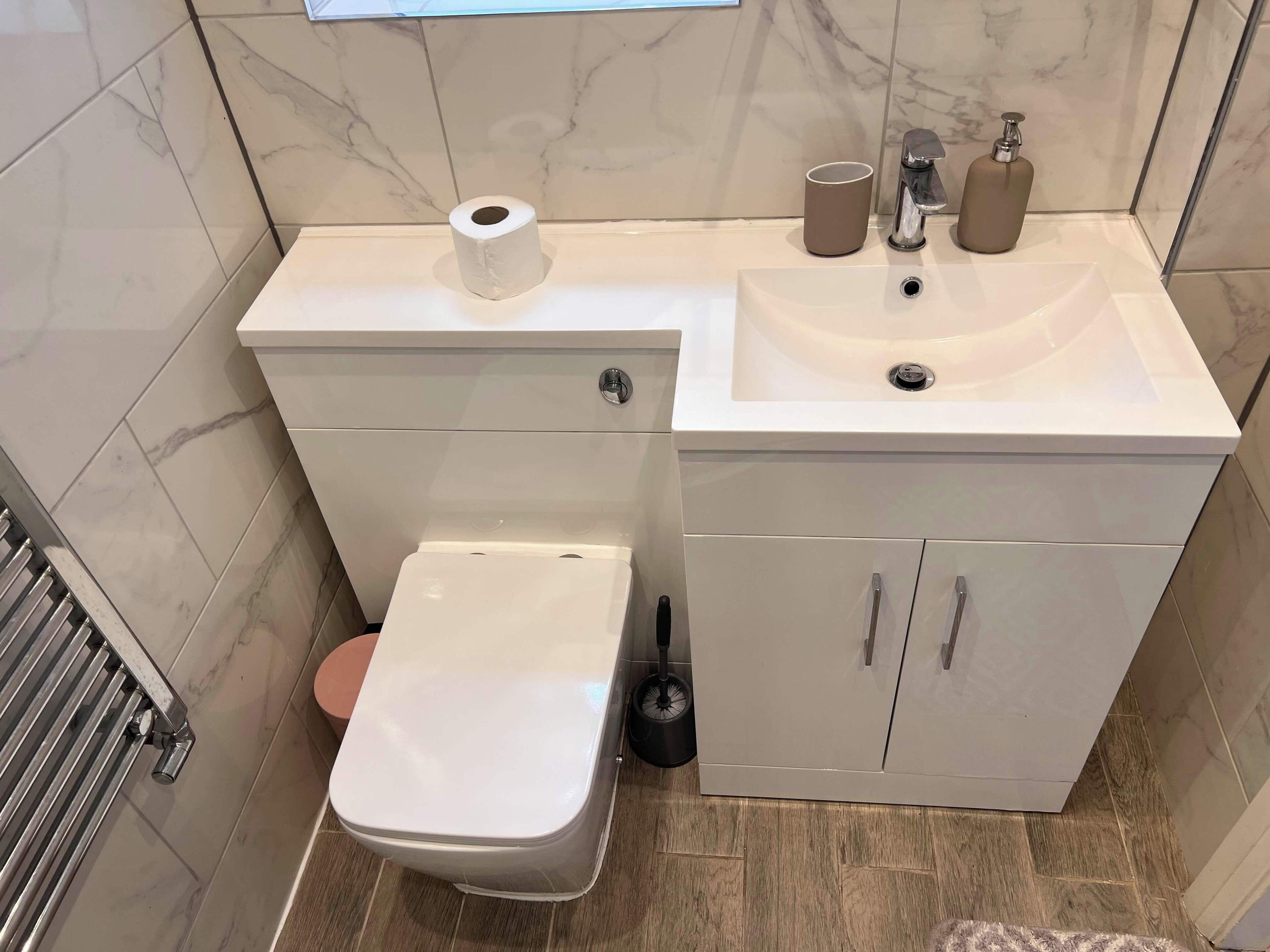 A compact bathroom with a toilet, sink, and storage cabinets.