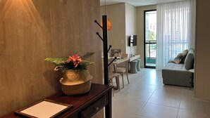 Una sala de estar moderna con una pared de acento de madera, un comedor con mesa y sillas, un sofá y un amplio ventanal con cortinas.