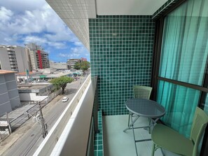A balcony with a view of a city street, a tiled wall, and a table with chairs. - Smart Stay Apto 405 Mandi Hospitalidade (Maceió)