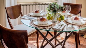Un coin repas avec une table dressée pour quatre personnes, une vue sur un immeuble doté d’une tour et une fenêtre avec des rideaux.