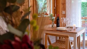 A wooden dining table with a bottle of wine, wine glasses, and a candle. - Résidence Bristol 12b by Interhome (Villars)