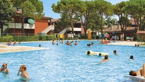 A public swimming pool with multiple people swimming and lounging. - Villaggio Azzurro by Interhome (Bibione)