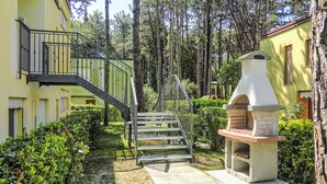 A courtyard with a staircase leading to a balcony, surrounded by greenery and trees.