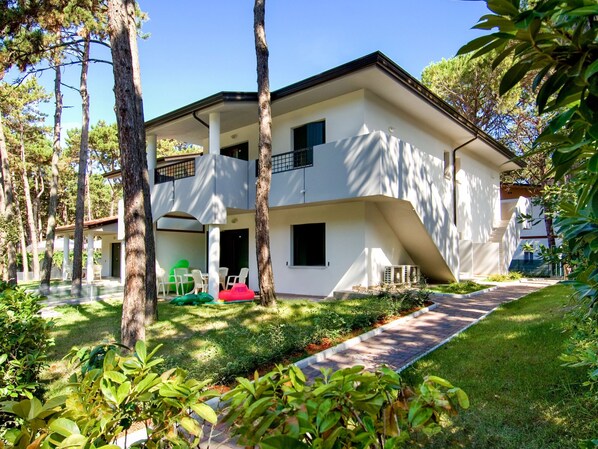 A modern two-story building with a flat roof and a covered outdoor seating area.