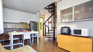 Ein kompakter Wohnraum mit Küche, Essbereich und einer Treppe zu einer oberen Ebene.