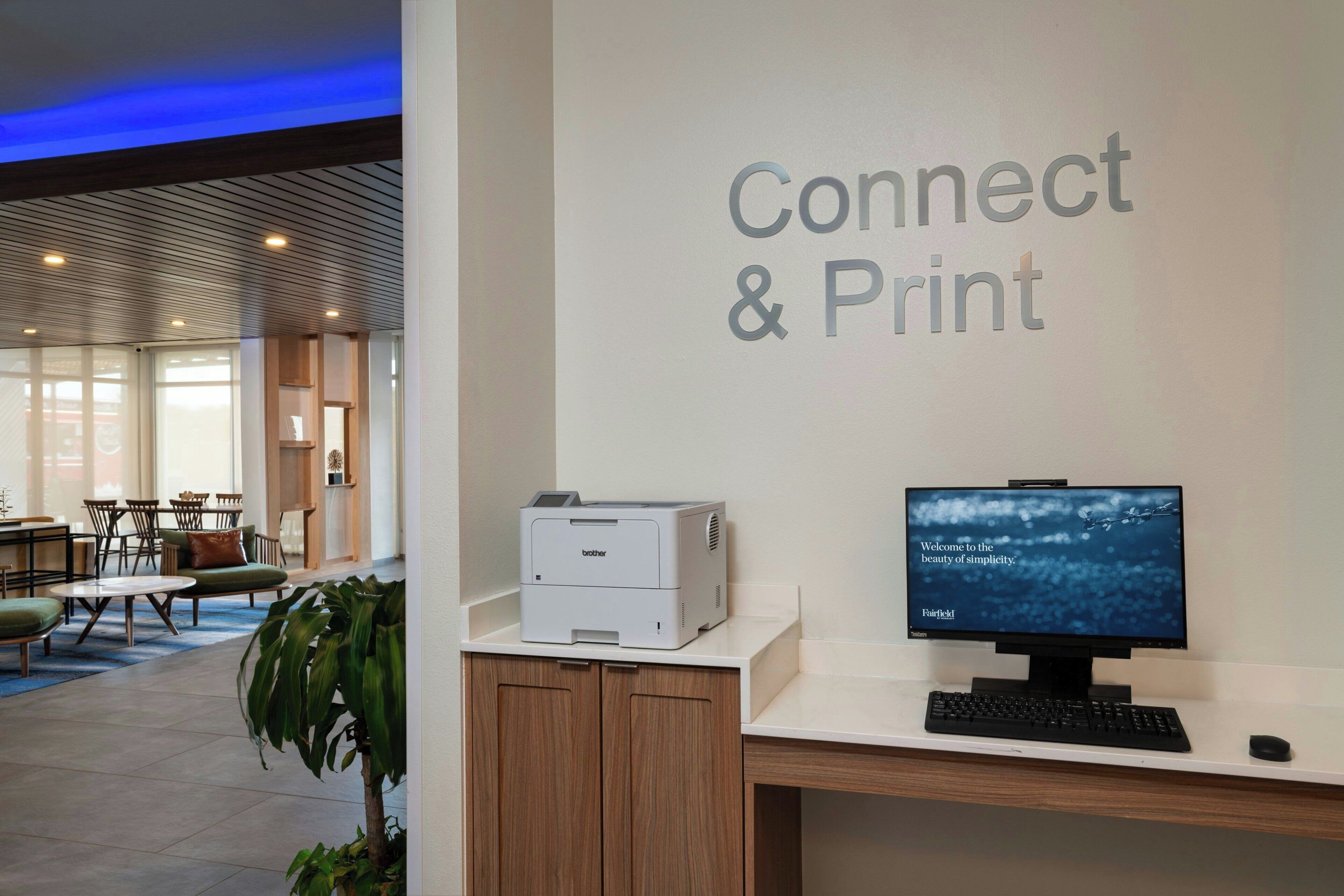 A reception desk with a Brother printer, a computer monitor, and a sign that reads "Connect & Print".
