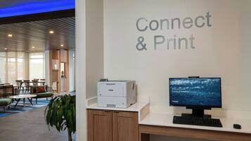 A reception desk with a Brother printer, a computer monitor, and a sign that reads "Connect & Print".