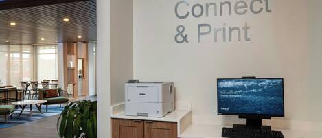 A reception desk with a Brother printer, a computer monitor, and a sign that reads "Connect & Print".