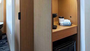 Una kitchenette compacta con microondas, un refrigerador pequeño y una cafetera en un estante.