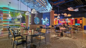 A modern restaurant with multiple dining areas, including a bar/lounge area with a colorful neon sign. - Moxy Ningbo Old Bund (Ningbo)