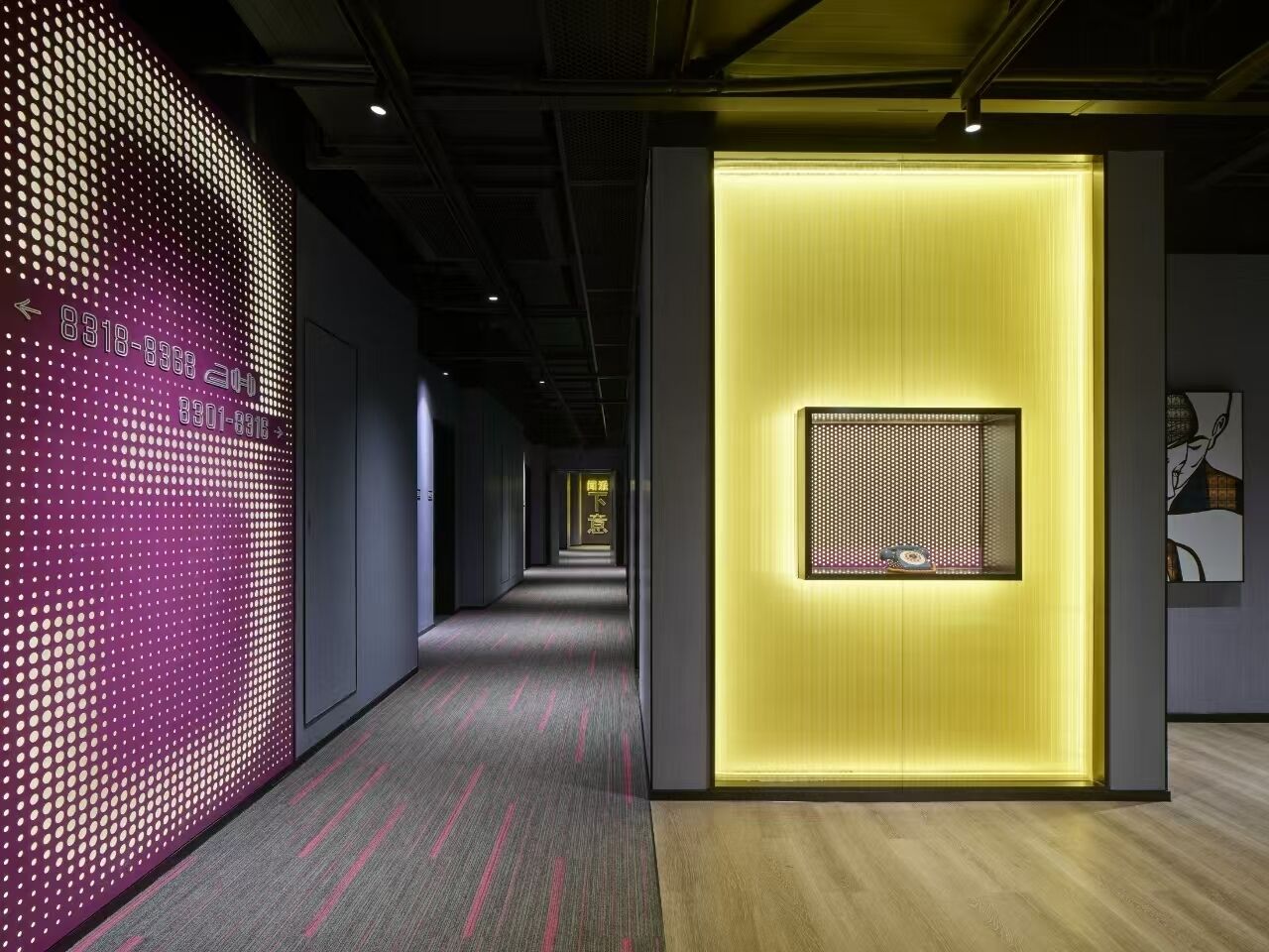 Un pasillo de diseño moderno, con una pantalla digital a la izquierda e iluminación en la pared derecha.