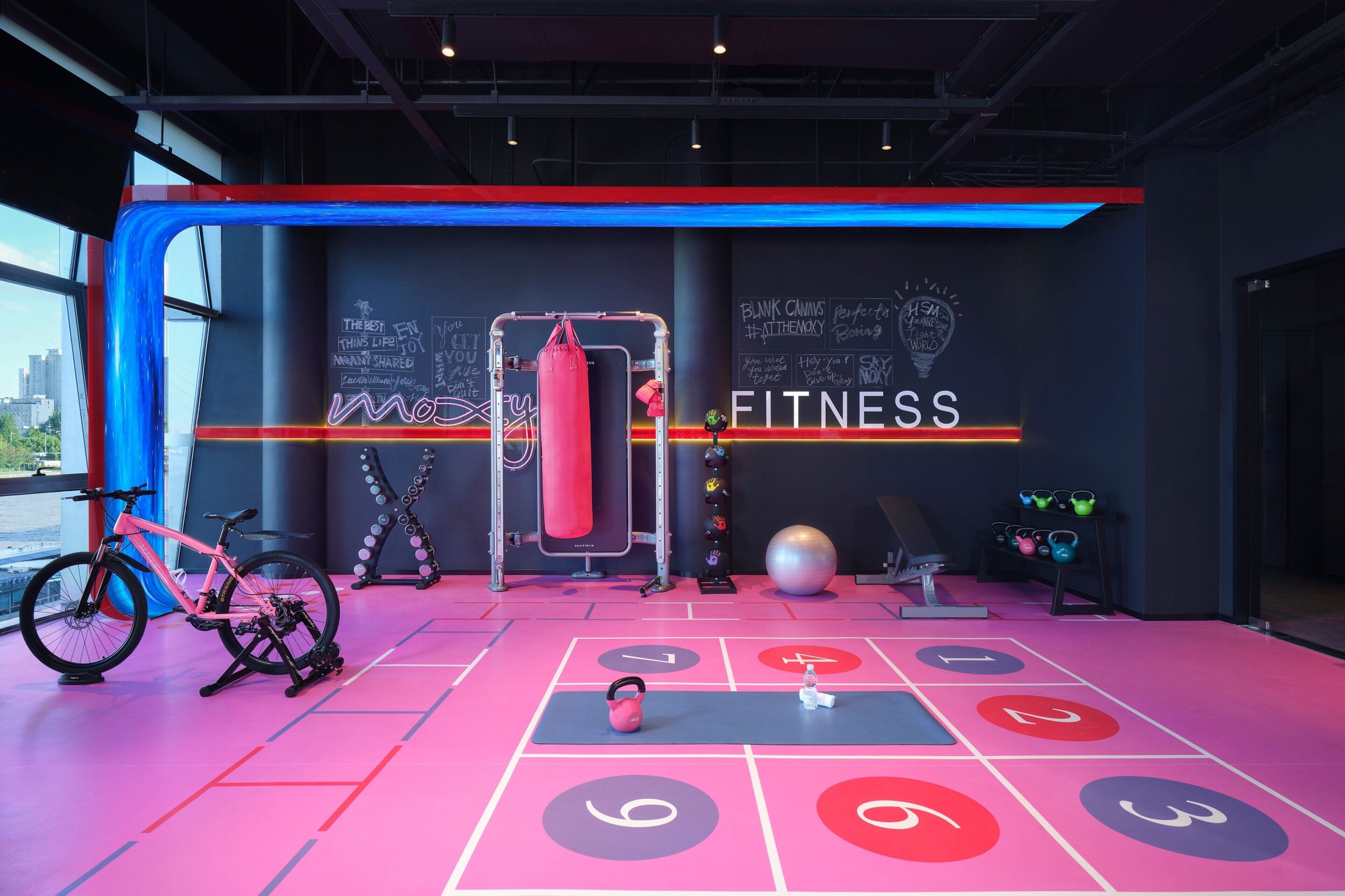 A modern fitness center with a large punching bag, a stationary bike, and a variety of weights.
