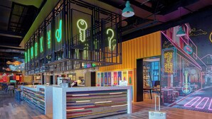 A modern bar area with neon signs, a colorful striped counter, and a wooden floor. - Moxy Ningbo Old Bund (Ningbo)