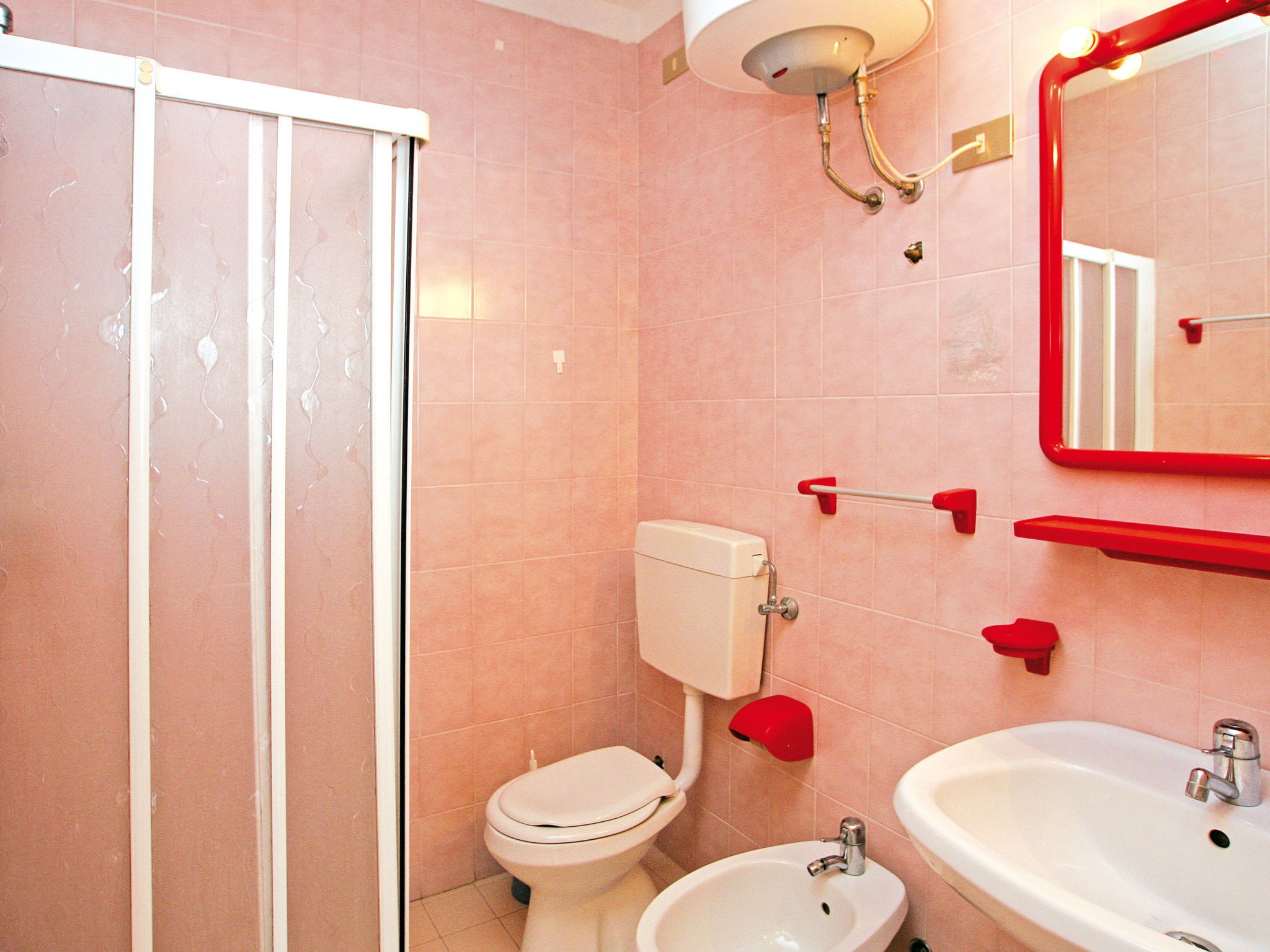 A bathroom with a toilet, bidet, sink, and a glass-enclosed shower.