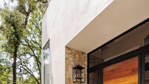 A modern house with a stone exterior, a wooden door, and a well-maintained lawn. - Casa Ripoll (Valle de Bravo)