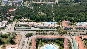 Vista aérea de un resort con un patio central, edificios circundantes y una playa al fondo.