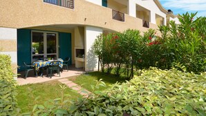 A two-story building with a covered outdoor seating area, a small garden, and a balcony with a railing. - Villaggio Marco Polo by Interhome (Bibione)