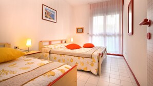 Habitación de hotel con dos camas, una ventana con cortinas, un cuadro en la pared y suelo de baldosas.