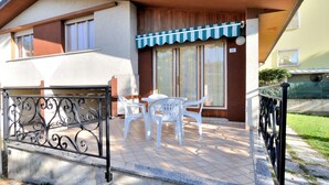 Una casa a due piani con un patio arredato con tavolo e sedie.