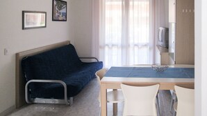 A small room with a bed, a table, two chairs, a TV, and a window with curtains. - Villaggio Capistrano by Interhome (Bibione)
