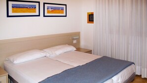 Ein Hotelzimmer mit einem Bett, einem Nachttisch und zwei gerahmten Bildern an der Wand.