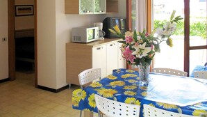 Une pièce comprenant une table à manger, des chaises, un four à micro-ondes, une machine à café et un vase avec des fleurs.