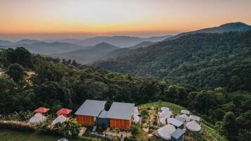 Un lodge aislado con varias cabañas y un edificio central, rodeado de un bosque frondoso y montañas.