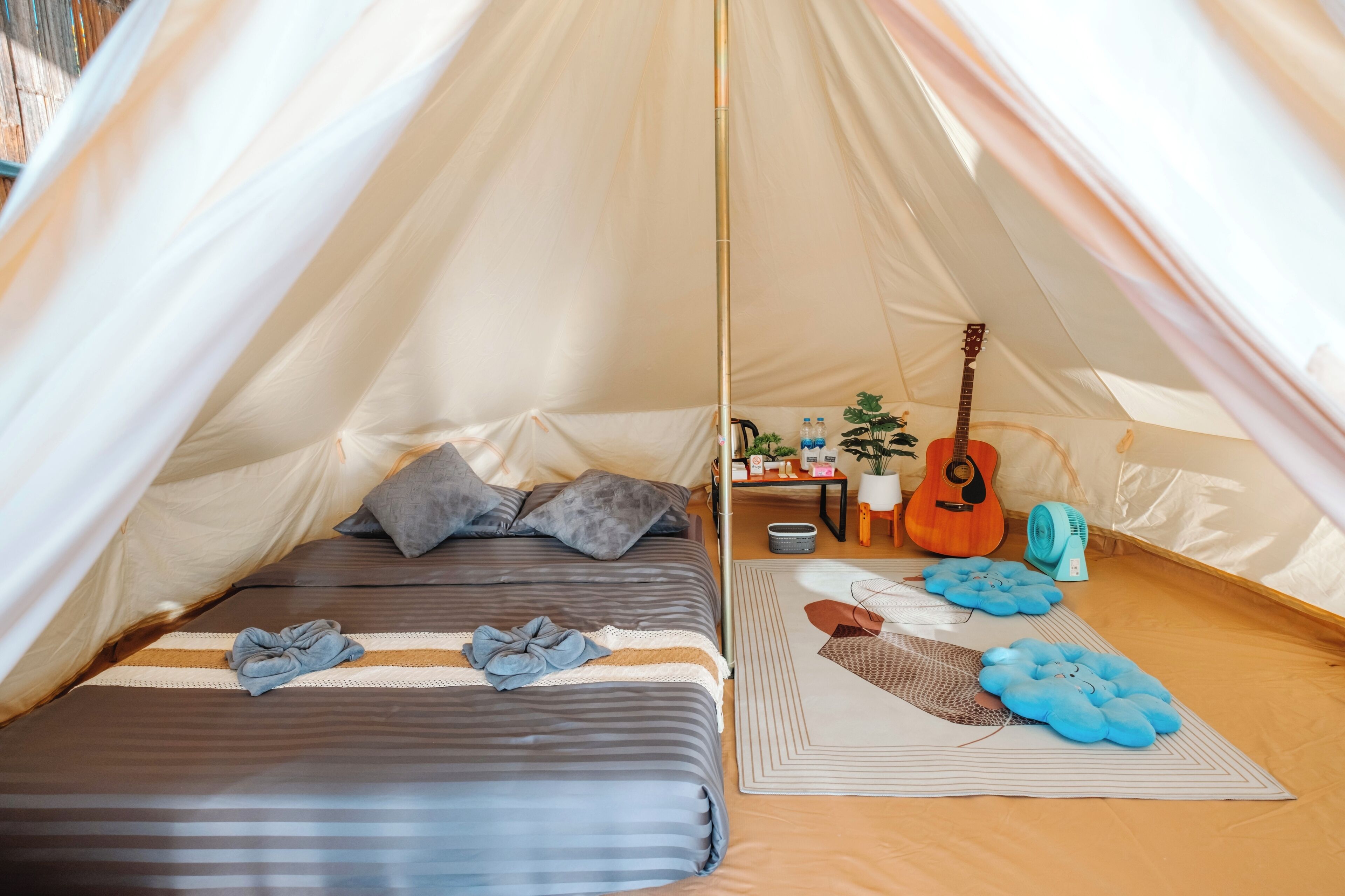 Ein gemütliches Zelt mit einem Bett, Kissen, einer Gitarre und Dekorationselementen.