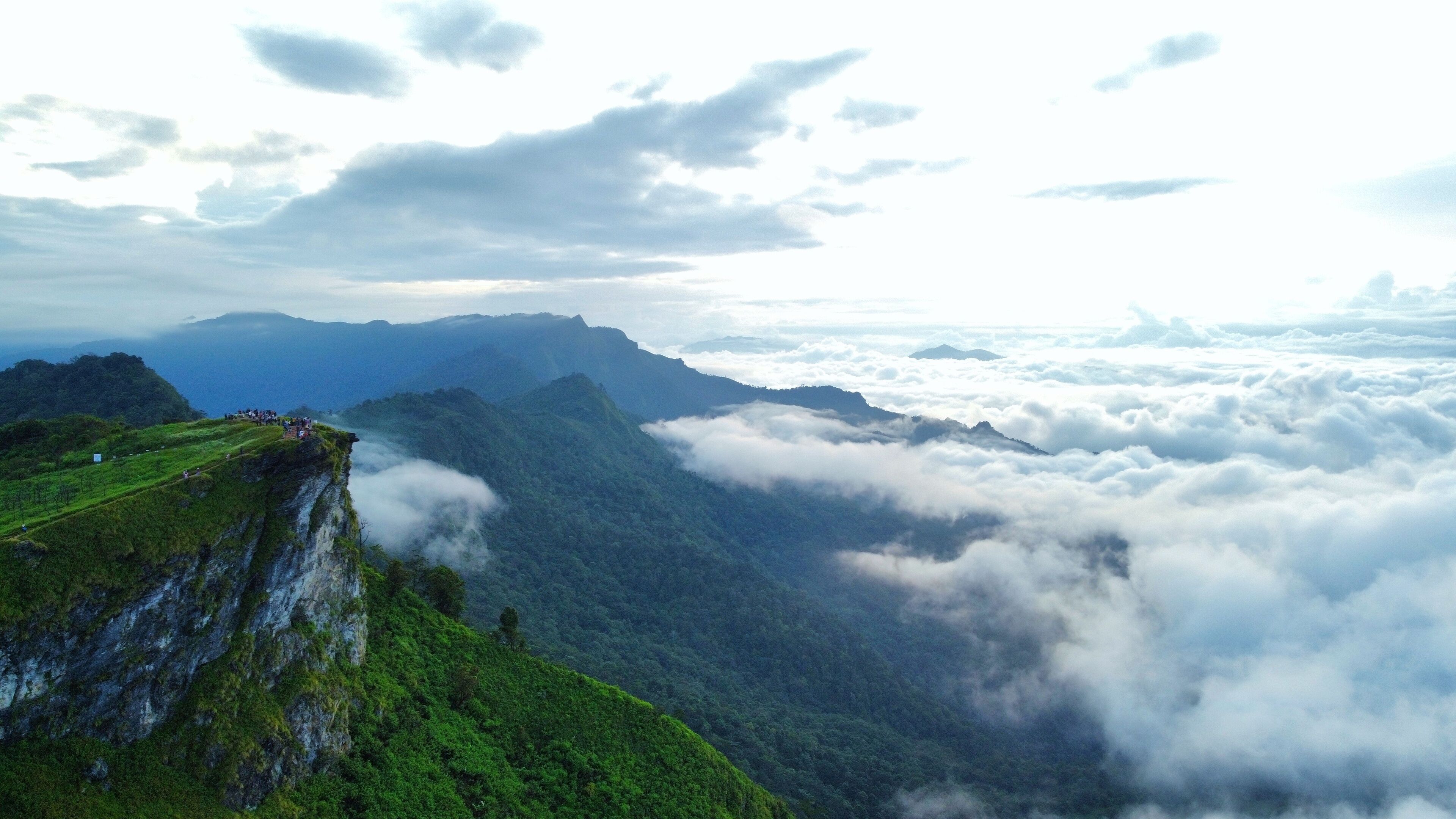 Eine Berglandschaft mit einer Aussichtsplattform über einem Tal aus Wolken.
