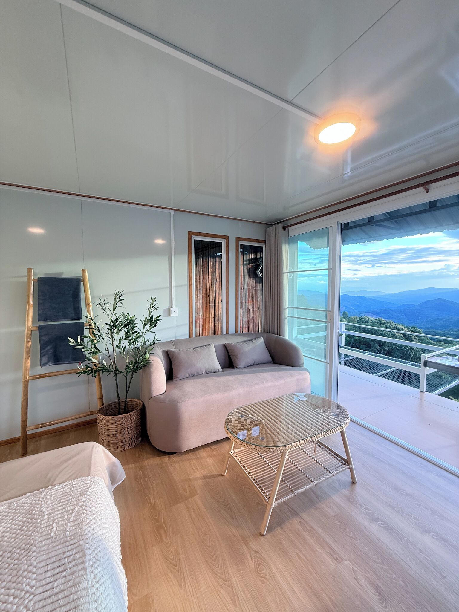 Un interior moderno con un sofá, una mesa de mimbre y vistas a las montañas a través de amplias ventanas.