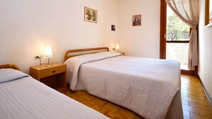 Une chambre avec deux lits, un plancher en bois et une fenêtre avec des rideaux.