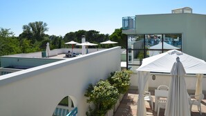 Een terras op het dak met buitenmeubilair, een zwembad en een glazen ruimte.