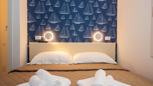 Ein Hotelzimmer mit einem Bett, zwei Kissen, einem Kopfteil und einer Wand mit Segelboot-Motiven.