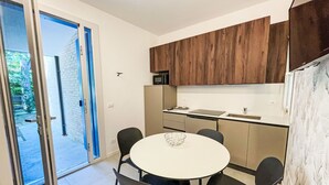 Eine moderne Küche mit Holzschränken, einer weißen Arbeitsplatte und einem runden Esstisch mit vier Stühlen.