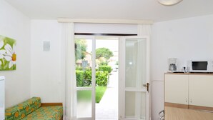 A compact kitchen with a dining area, a sofa, and a view of the outside. - Villaggio Tivoli by Interhome (Bibione)