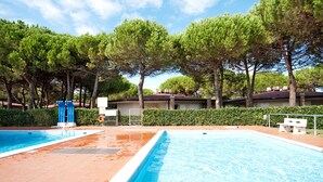 A swimming pool with two separate sections, surrounded by trees and a hedge. - Villaggio Tivoli by Interhome (Bibione)